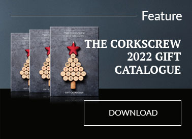 Three copies of the Corkscrew Christmas Gift catalogue in front of a grey & black background