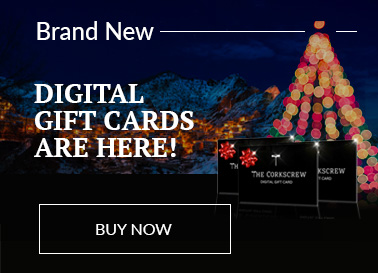 Corkscrew Gift Cards in front of a snowy mountain scene at night lit by houselights and Christmas tree lights.