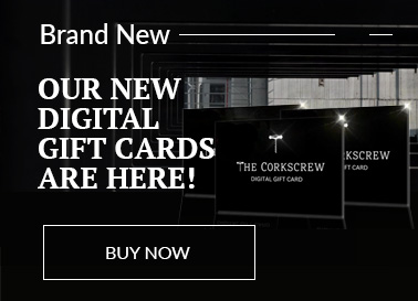 Corkscrew Gift Cards in front of a snowy mountain scene at night lit by houselights and Christmas tree lights.